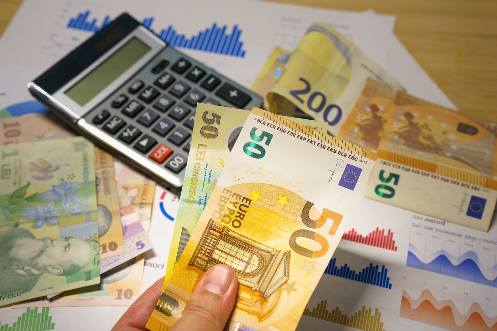 Escritorio con billetes de dólar, calculadora y documentos que representan salarios y horas de trabajo