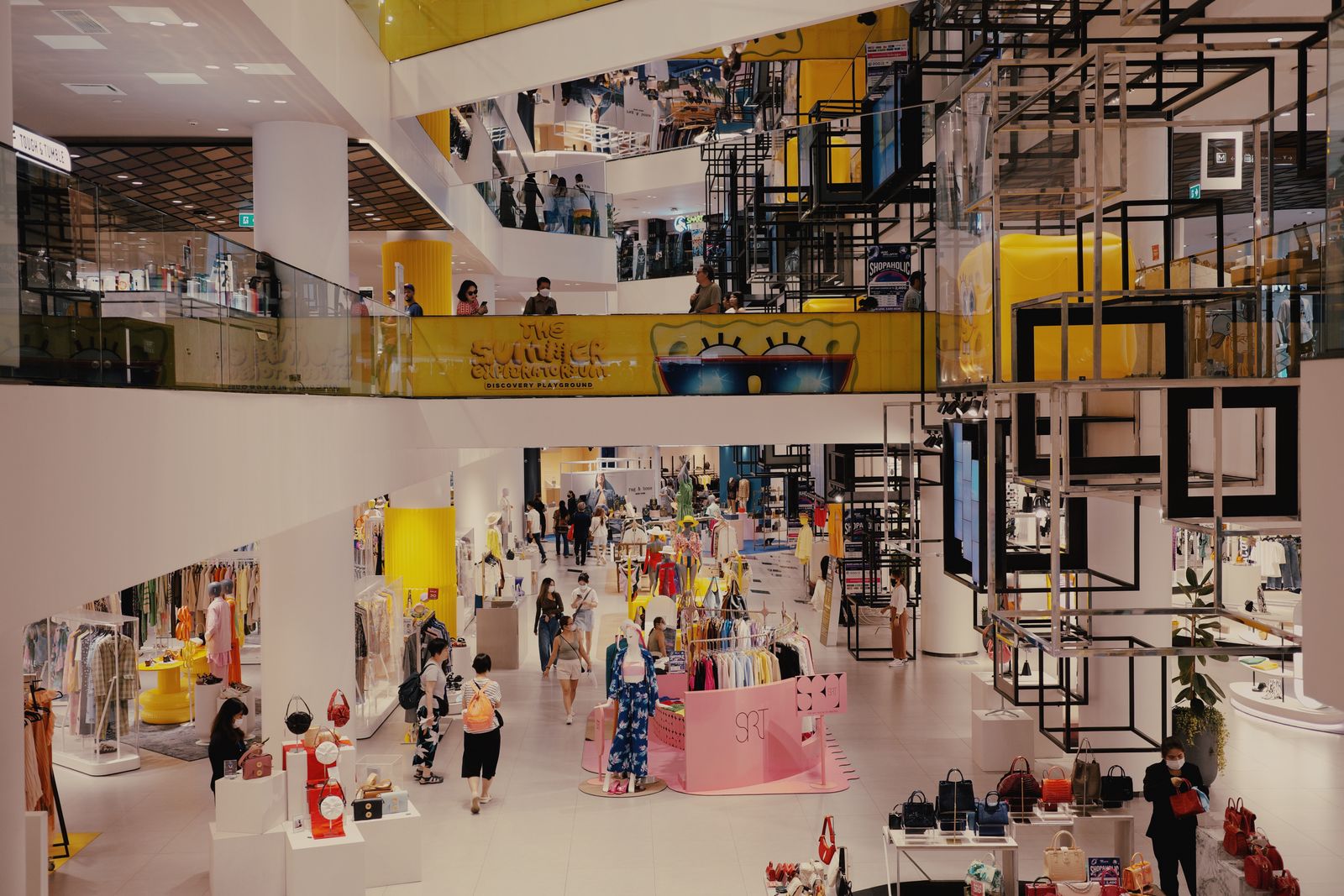 Interior de un centro comercial con tiendas de moda y consumidores