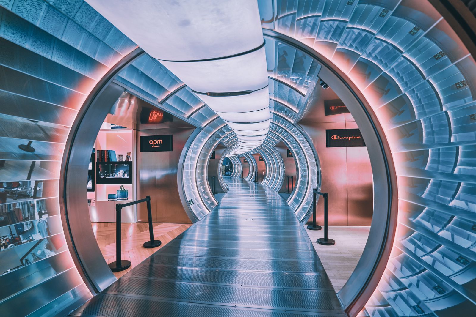 Interior de un centro comercial moderno con pasillos amplios y escaleras mecánicas