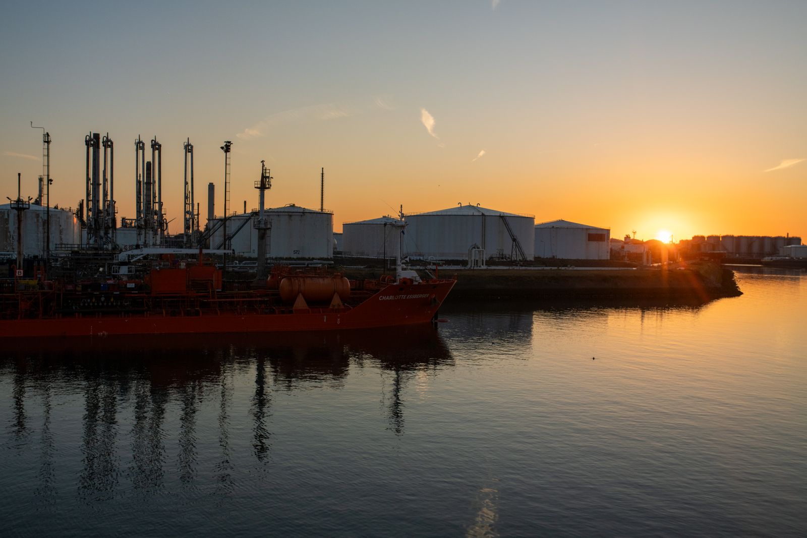 Buques tanque y tanques de almacenamiento en un puerto petrolero al atardecer