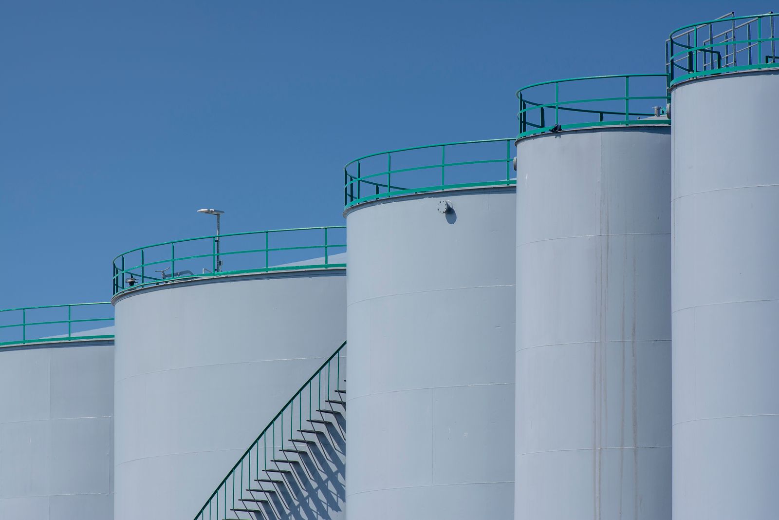 Instalaciones industriales de una petrolera con tanques y tuberías al atardecer