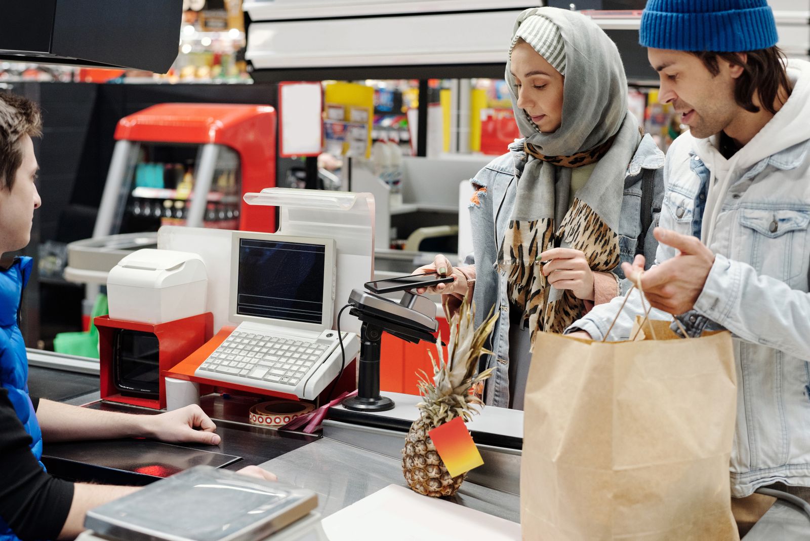 Persona escaneando un código QR de un producto en una estantería de supermercado con un teléfono móvil