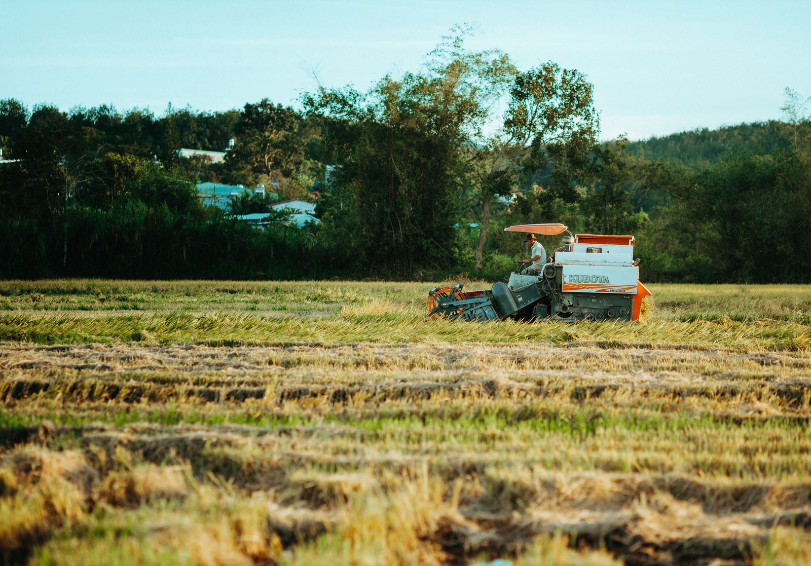 Campos de cultivo con maquinaria agrícola trabajando al atardecer