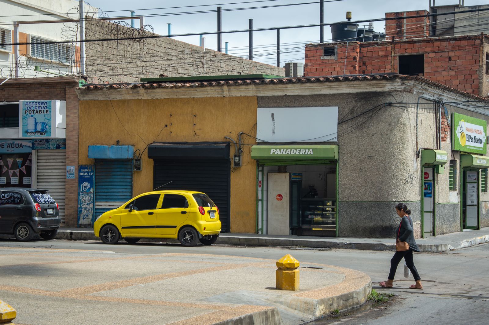 Calle comercial con negocios y peatones en una ciudad latinoamericana